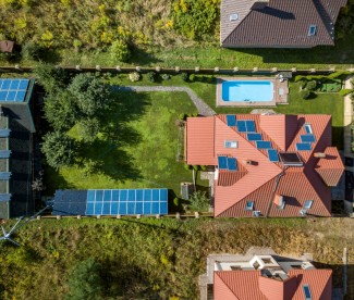 Aerial view of rural residential area with private homes between green fields at sunrise.