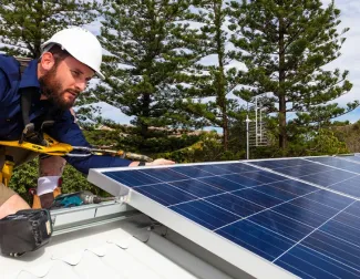 Solar installer installing panels on roof