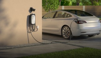 White Tesla plugged into electric charger for charging.