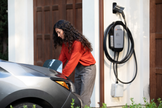 Woman with Enphase EV charger on wall