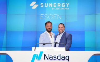 Luke Guy and Tony Hruby standing behind a Nasdaq podium at a corporate event, with the logos ‘SUNERGY by ZEO ENERGY’ and ‘ESGEN’ displayed on a large blue wall in the background.