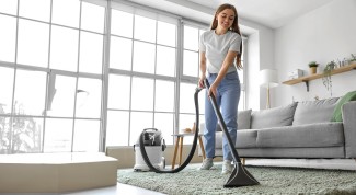 Woman cleaning carpet with an energy-efficient vacuum to help reduce energy consumption