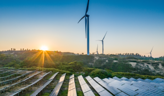 Solar panels and wind turbines generating renewable energy at sunrise on a hilly landscape