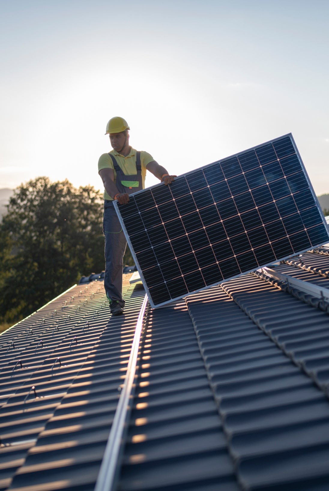 A man standing on a roof with a solar panel, harnessing renewable energy for a sustainable future.